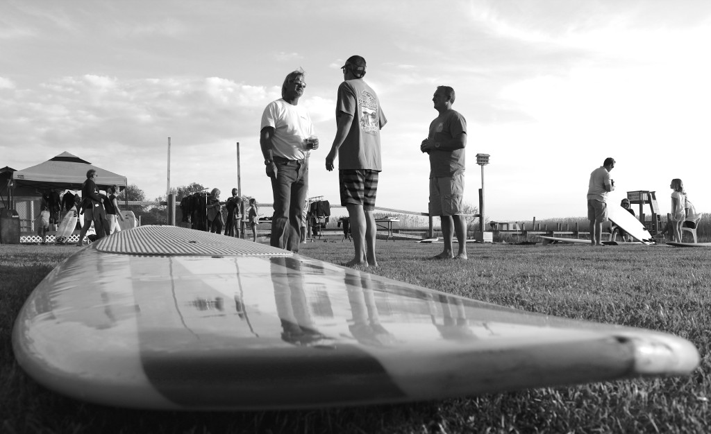 James Barton, center left, chats at Baja Restaurant on Sunday, May 3, near a very long surfboard available at the swap meet. [John-Henry Doucette/The Princess Anne Independent News]