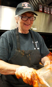 Sue Bell puts the rub one before the pork goes in the smoker. [John-Henry Doucette/The Princess Anne Independent News]