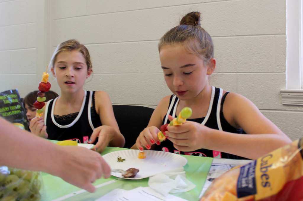 Charlotte Scalzi, 10, and Madi Brown, 11, assemble their own snacks of fruit and cheese while being served some Nutella. Both girls are from Lago Mar. [John-Henry Doucette/The Princess Anne Independent News]