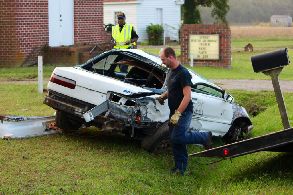Lonnie Twiford, after righting a car that came to rest upside down in a crash, prepares to bring the vehicle aboard a Sandbridge Towing truck. In the background is Virginia Beach police Chaplain Albert Mentore, who assisted at the scene of the crash, in which three people were injured on Tuesday, Sept. 29, 2015. [John-Henry Doucette/The Princess Anne Independent News]