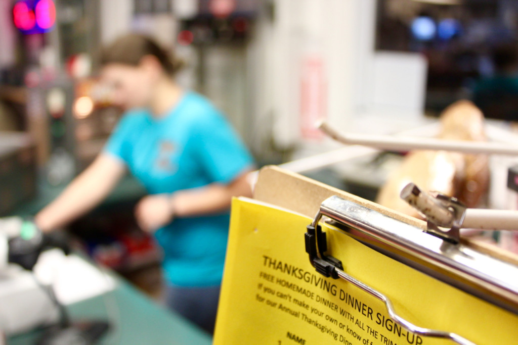 Brittany Hamilton, co-owner and manager at the Blackwater Trading Post, cleans up for the evening near the clipboard where names — even “Jane or John Doe” for those who may not want to use their name  — are written to reserve free Thanksgiving meals [John-Henry Doucette/The Princess Anne Indepdnent News]