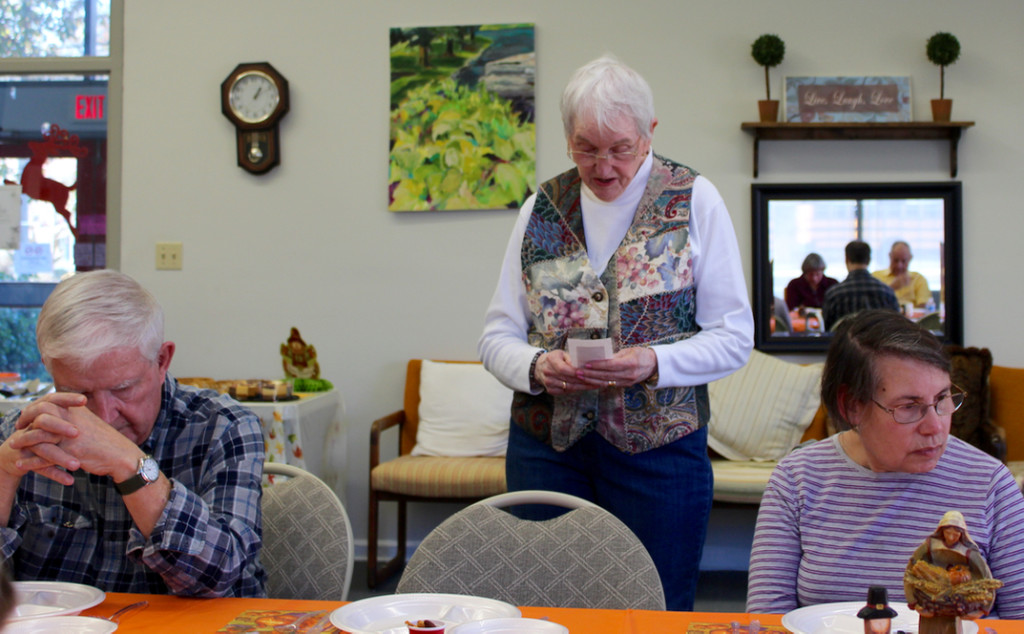 Sara Schauer says a blessing before the Thanksgiving meal she started at the Senior Resource Center, Inc., several years ago. It’s a pot luck that brings together people who appreciate the center’s work and each other. [John-Henry Doucette/The Princess Anne Independent News]