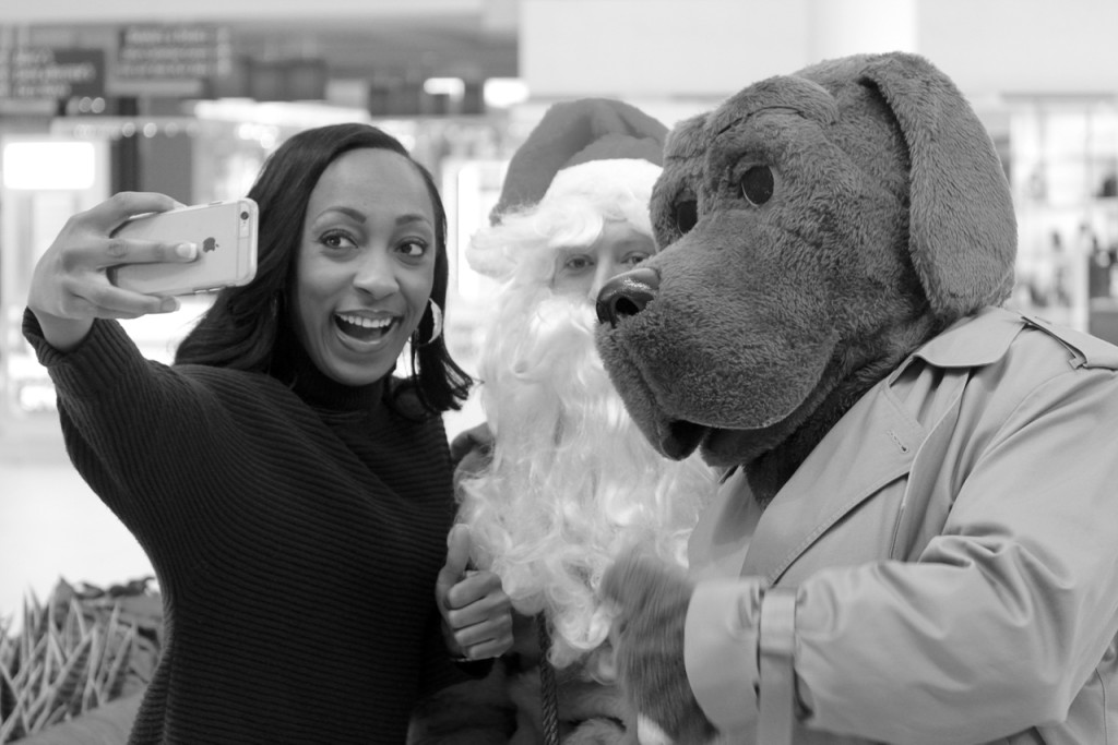Reporter Stefania Okolie of WTKR-TV takes a selfie with Santa and McGruff. [Th Princess Anne Independent News]