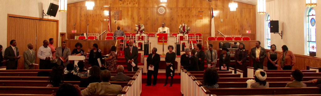 Wilson is seen, at center, as many people who help the church run stand before the congregation and promise to serve and “walk together in love for one another.”