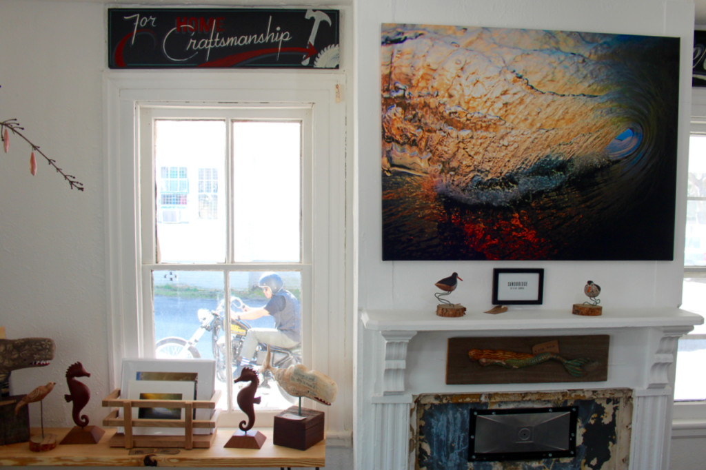 Part of the front room of the Tar Roof is seen while, through the window, a friend of the owners, Glenn Newland, pulls up on a motorcycle during a visit to the Pungo gallery. [John-Henry Doucette/The Princess Anne Independent News] 