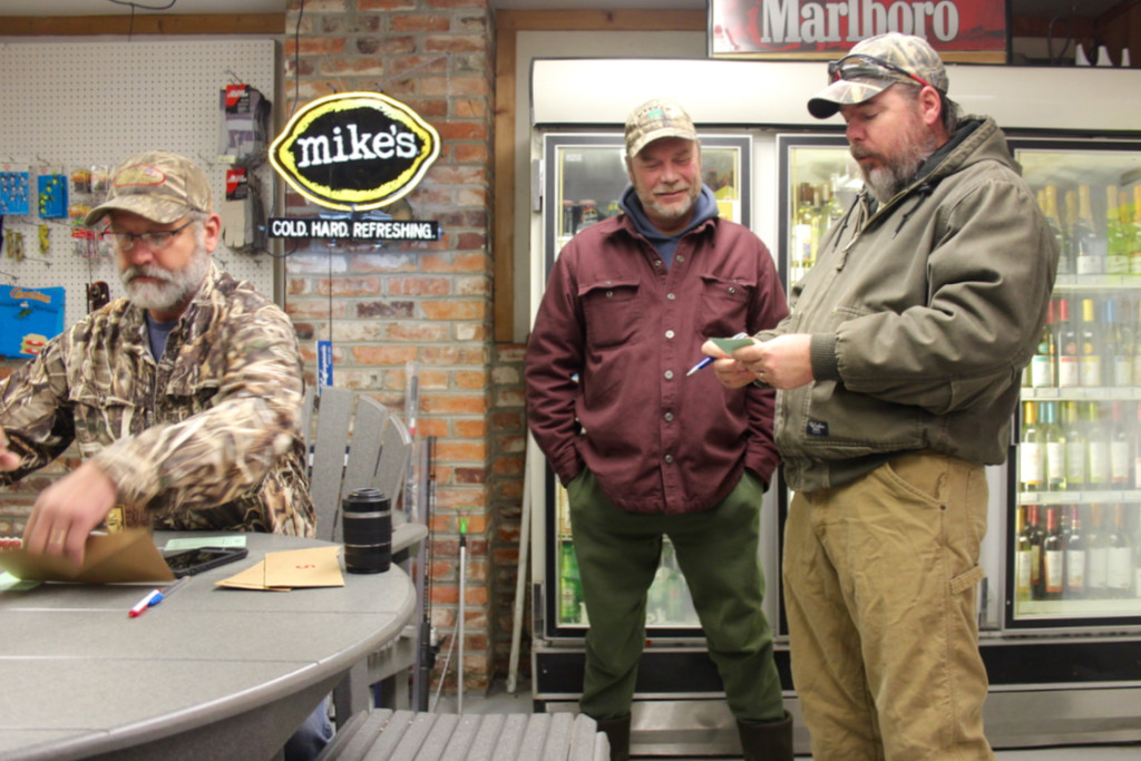 Brian Smith and Donald Smith, brothers from Knotts Island, N.C., wait to get a blind assigned to the during an early morning visit at the Knotts Island Market early Saturday morning on the last weekend of the season.  At left is Carl Coviello, who helps run the draw with Cliff Scott. [John-Henry Doucette/The Princess Anne Independent News]