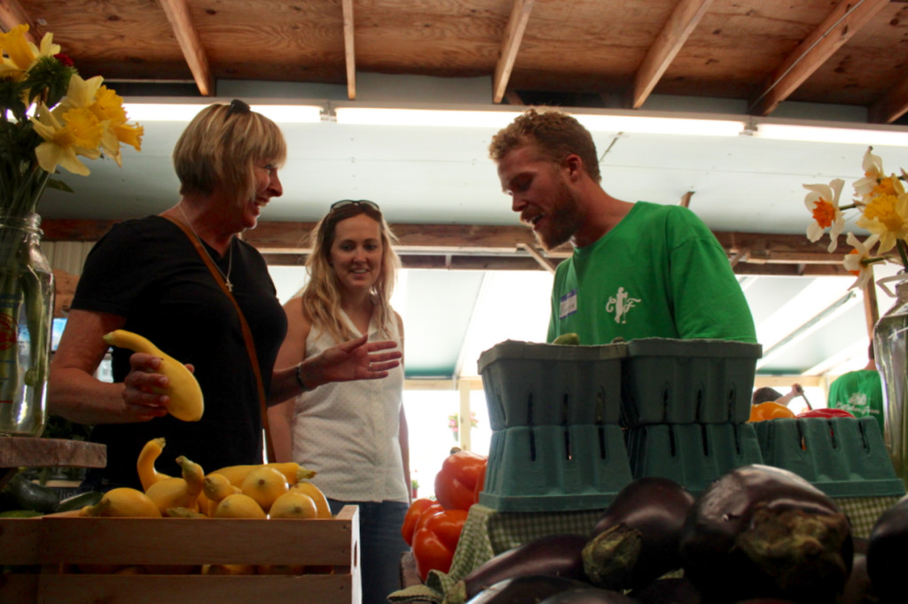 Hunter Walsh of the Cullipher family shares a laugh with customers at the new Cullipher Farm Market at 1065 First Colonial Road, the former location of Stoney’s Produce. With him are Cindy Maloney of Great Neck Meadows and her daughter-in-law, Lauren Maloney of Shadowlawn. Cindy Maloney said she was sorry to see Stoney’s go, but she was glad another market had opened at the spot. [John-Henry Doucette/The Princess Anne Independent News]