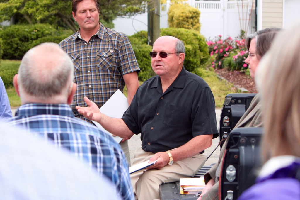 Tom Fraim, a Sandbridge resident who leads the beaches and waterways advisory commission, leads a meeting that started in the parking lot at Sandbridge Community Chapel United Methodist Church prior to a van tour of the community. The commission is reviewing the issue of large homes that host events, often weddings. [John-Henry Doucette/The Princess Anne Independent News]