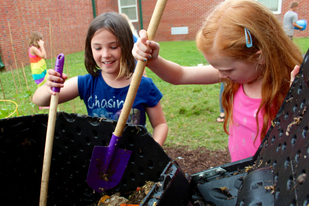 Maggie Kelley, 10, of Blackwater, and Zoey Walker, 9, of Pungo use shovels to break down organic matter in a compost tumble at Creeds Elementary School on Friday, June 17, 2016. [John-Henry Doucette/The Princess Anne Independent News] 