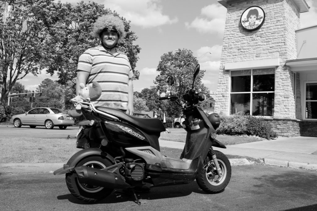 Josh Cantrell, 27, of Salem Lakes is seen with his Yamaha Zuma near Princess Anne Road and Tiffany Lane. He sports a wig on his helmet, which has gotten him pulled over. [John-Henry Doucette/The Princess Anne Independent News]
