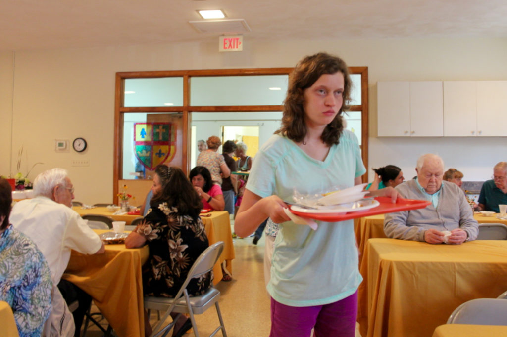 Myra Fisher, 16, of Lago Mar helps clear places during the luncheon. [John-Henry Doucette/The Princess Anne Independent News]