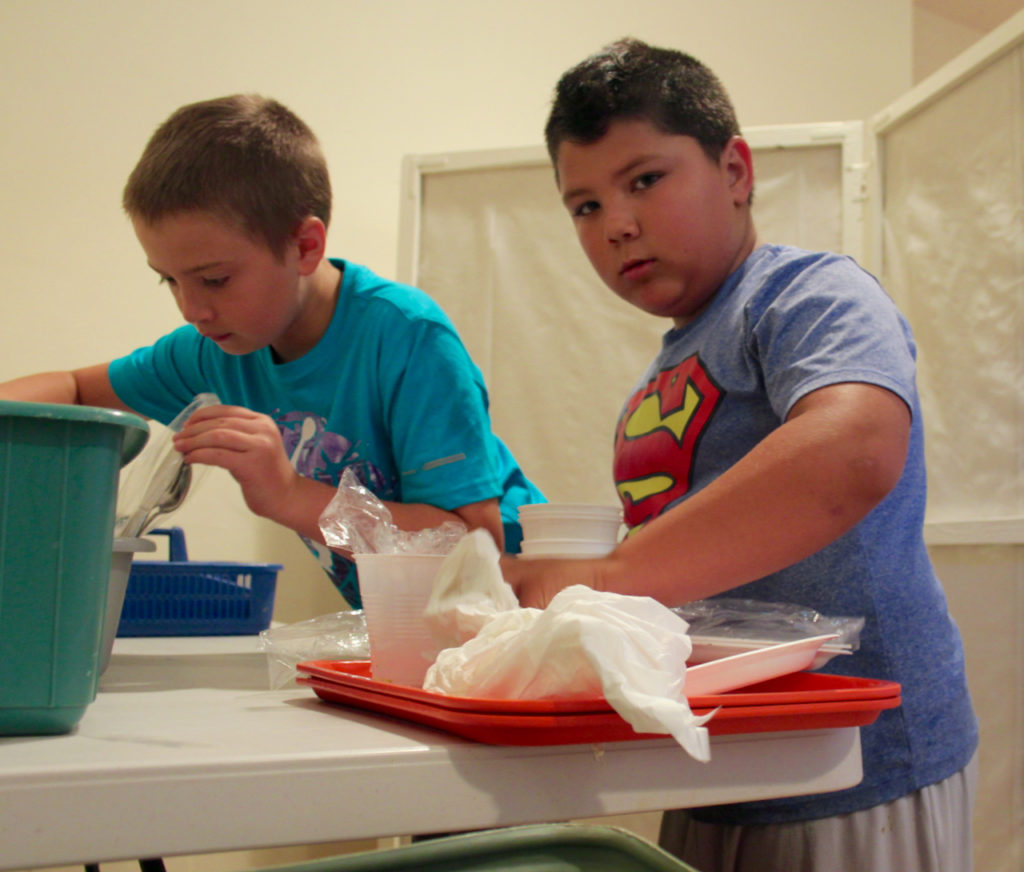 Andrew Stacy, 11, and Nic Windsor, 9, help bus tables. [John-Henry Doucette/The Princess Anne Independent News]