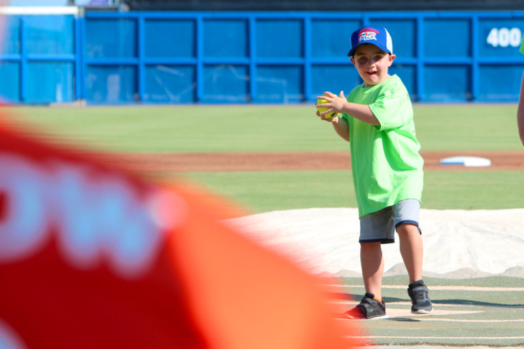 Logan Morean, 4, of Suffolk throws the opening pitch to Chesapeake Capt. Lawrence Matthews, Morean’s uncle, before the charity game begins at Harbor Park. [John-Henry Doucette/The Princess Anne Independent News]