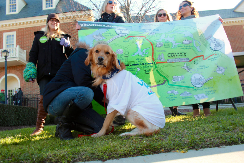 Advocates for light rail, with a dog keeping them company, hold a Virginia Beach Connex sign during a rally at City Hall in April. [John-Henry Doucette/The Princess Anne Independent News]