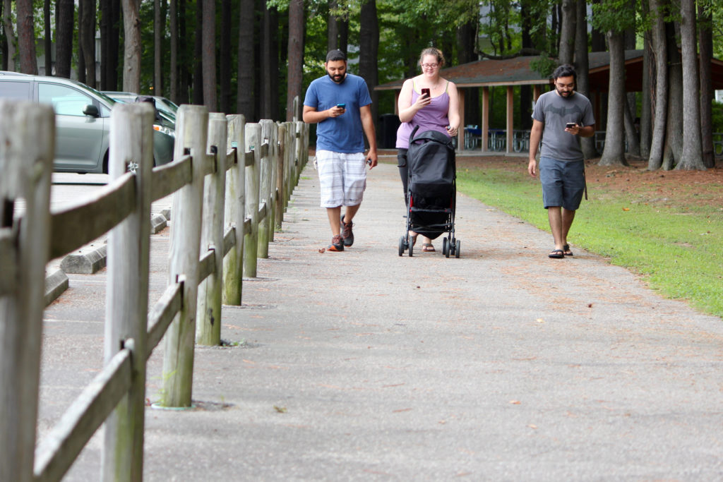 The Querashi family walks at Red Wing Park, mobile devices in tow. They are Rahman Querashi, his wife, Heather Querashi, their daughter, 2-month-old, Zaara, and Rahman’s brother, Raheem Quuerashi. [John-Henry Doucette/The Princess Anne Independent News]