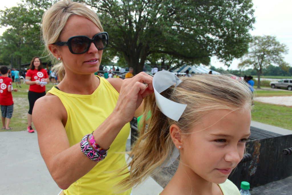 Tasha Frederick of Sandbridge ties a ribbon into the hair of Laney Frederick, 9. Ribbons of different colors raise awareness or are a remembrance of someone lost. [John-Henry Doucette/The Princess Anne Independent News]