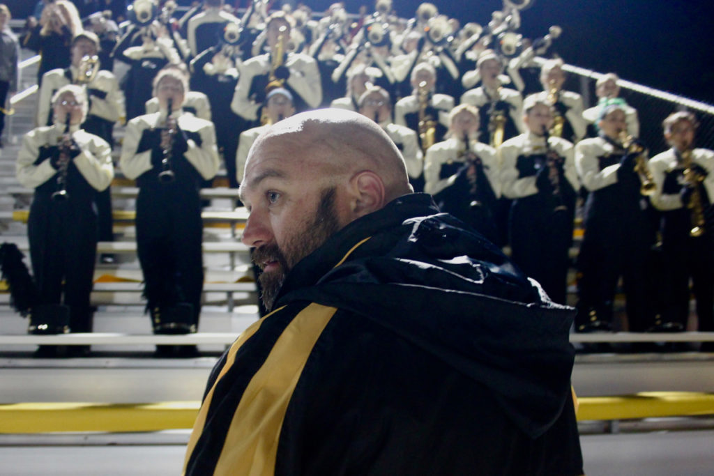 Band director Cameron Baker watches the game to help direct the band while it plays in the stands. [John-Henry Doucette/The Princess Anne Independent News]