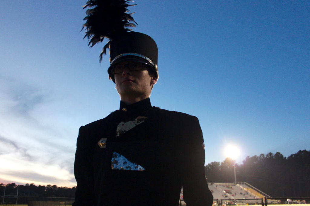 Noah Bilger, the drum major, waits for the band to take the field to play while the Friday night lights shine behind him. [John-Henry Doucette/The Princess Anne Independent News]