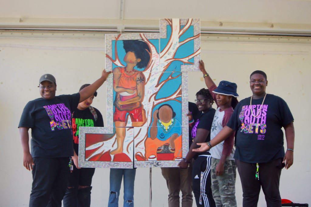 Young people show how the panels of the painting unite. [John-Henry Doucette/The Princess Anne Independent News]